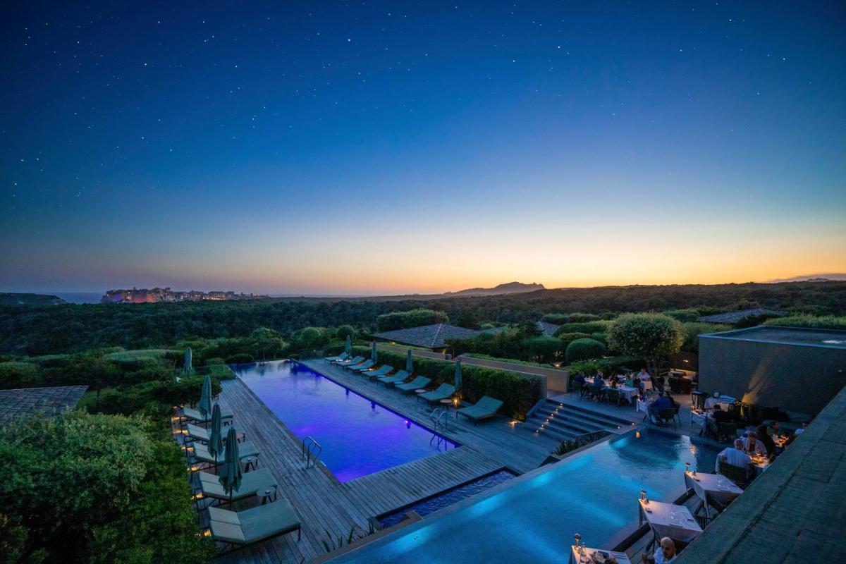 une vue d'une piscine dans un complexe hôtelier la nuit dans l'établissement Hôtel & Spa Version Maquis Citadelle, à Bonifacio une vue d'une piscine dans un complexe hôtelier la nuit dans l'établissement Hôtel & Spa Version Maquis Citadelle, à Bonifacio