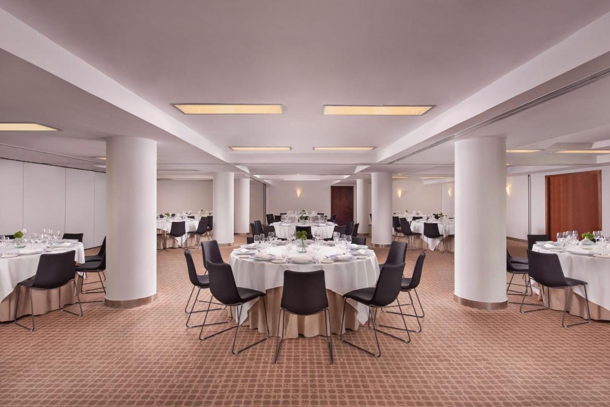 Un salón de banquetes con mesas y sillas blancas. en Le Meridien Barcelona, en Barcelona 171 fotos más