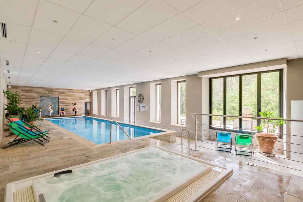 une grande piscine avec bain à remous dans un bâtiment dans l'établissement La Cachette, à Dieulefit