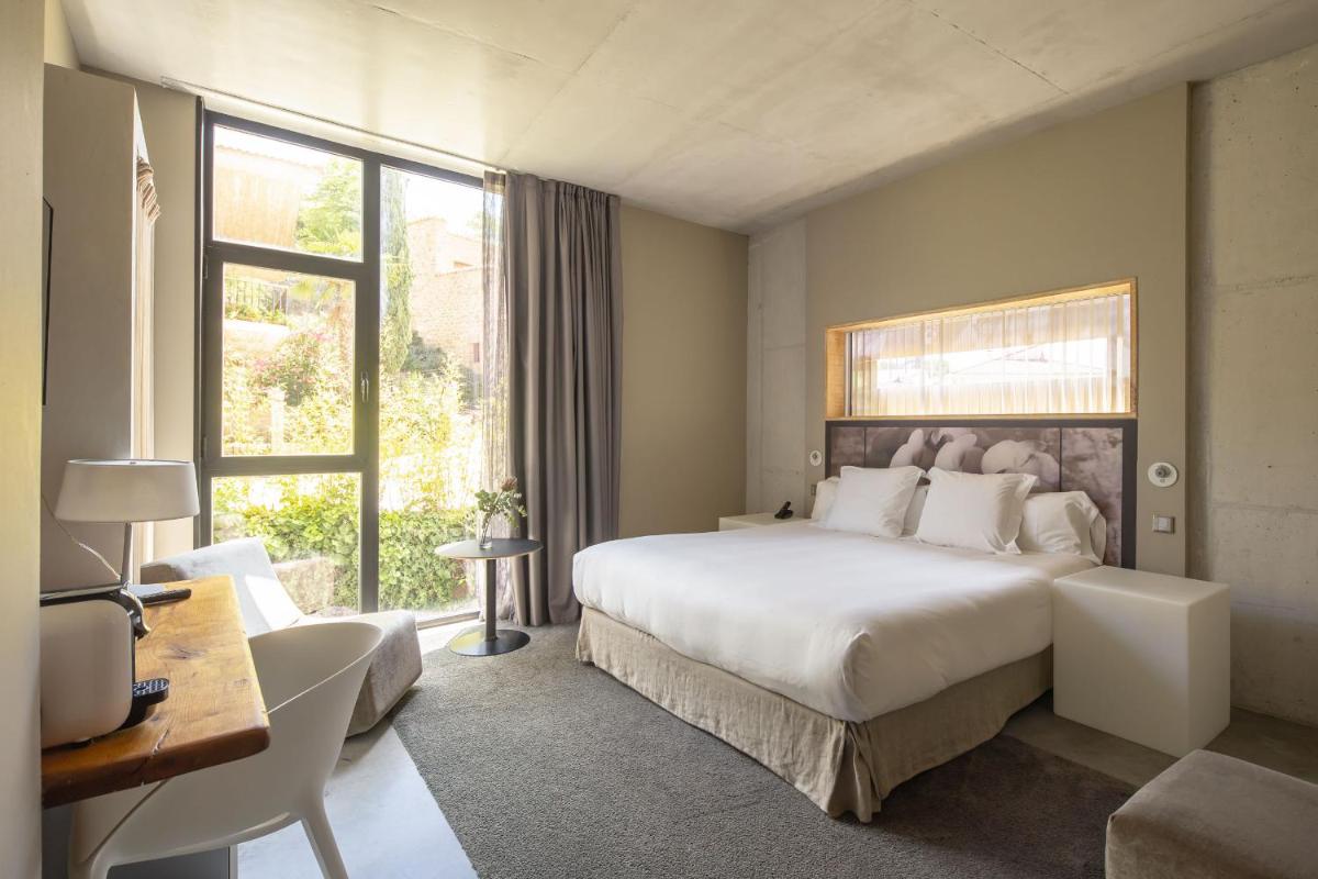 Un dormitorio con una gran cama blanca y un escritorio. en Hotel Viura, en Villabuena de Álava