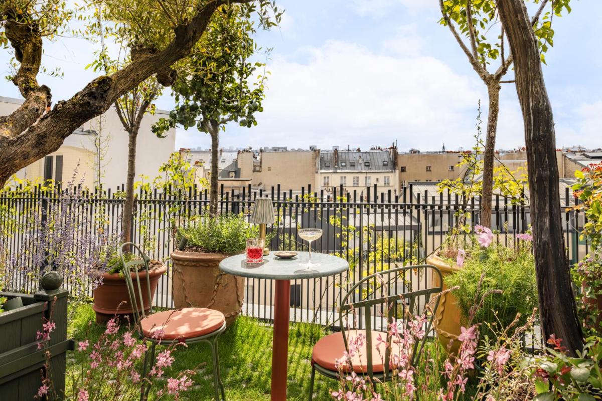 - un petit jardin avec une table et des chaises devant une clôture dans l'établissement La Fantaisie, à Paris
