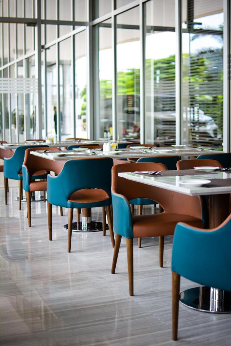 a dining room with tables and chairs and windows at Holiday Inn New Delhi Aerocity by IHG in New Delhi