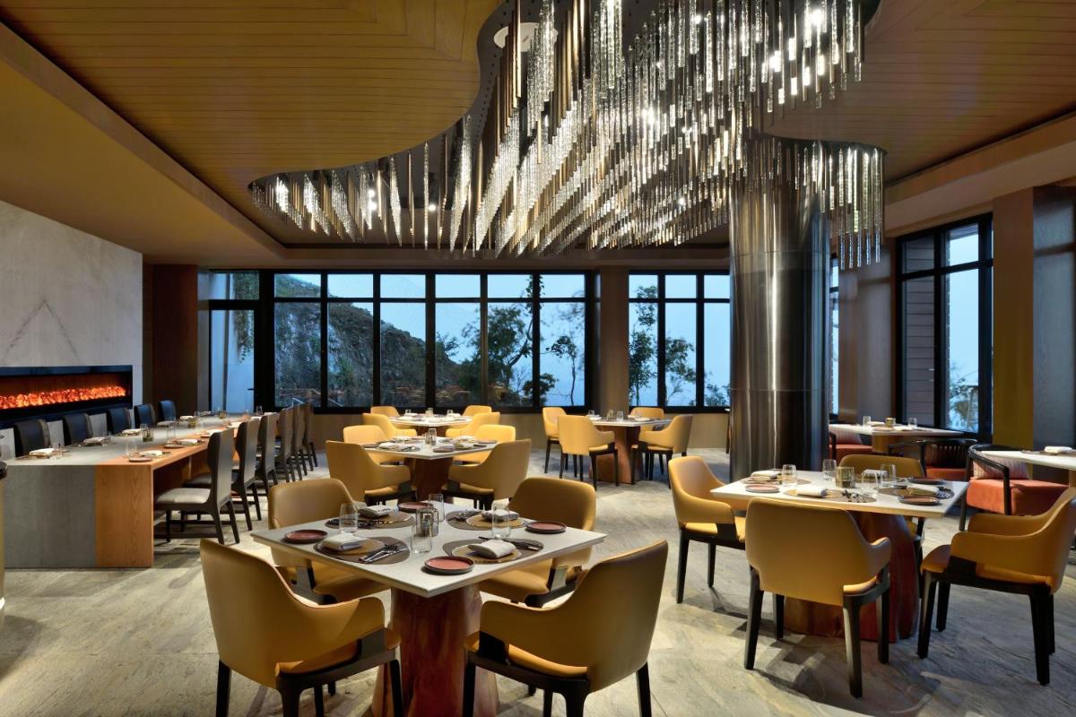 a restaurant with tables and chairs and a chandelier at The Westin Resort & Spa Himalayas in Rishīkesh