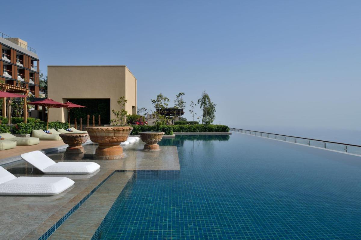 a swimming pool with white lounge chairs next to a building at The Westin Resort & Spa Himalayas in Rishīkesh
