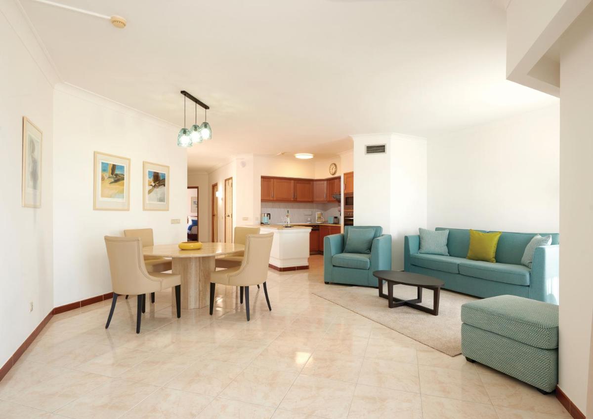 uma sala de estar com uma mesa e um sofá azul em Four Seasons Vilamoura em Vilamoura