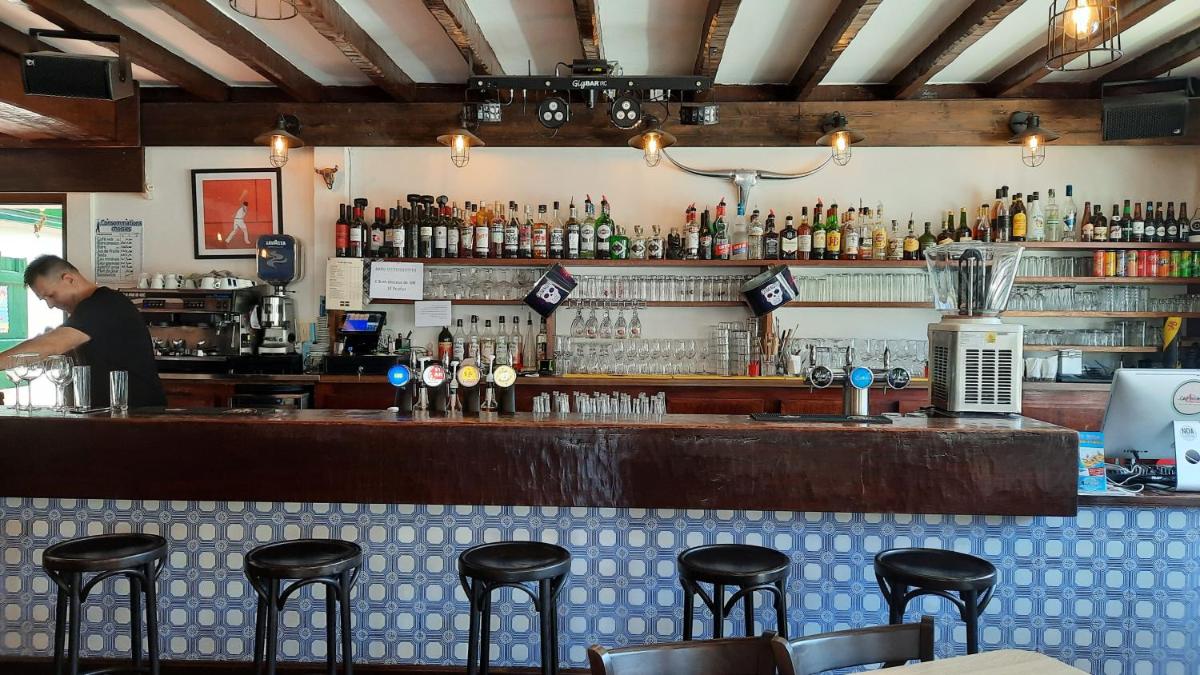 un bar avec un homme debout derrière un comptoir dans l'établissement Hotel Trinquet, à Saint-Pée-sur-Nivelle