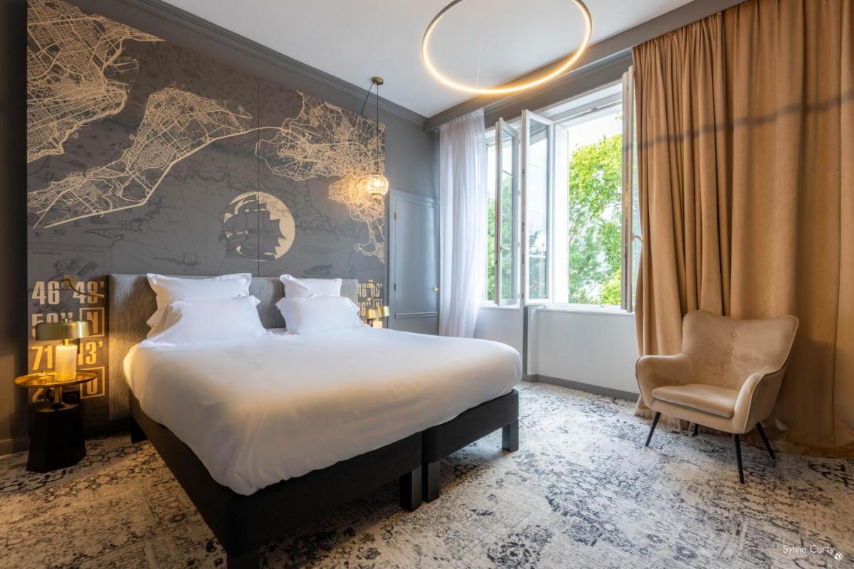 une chambre avec un grand lit et une chaise dans l'établissement Le Champlain, à La Rochelle