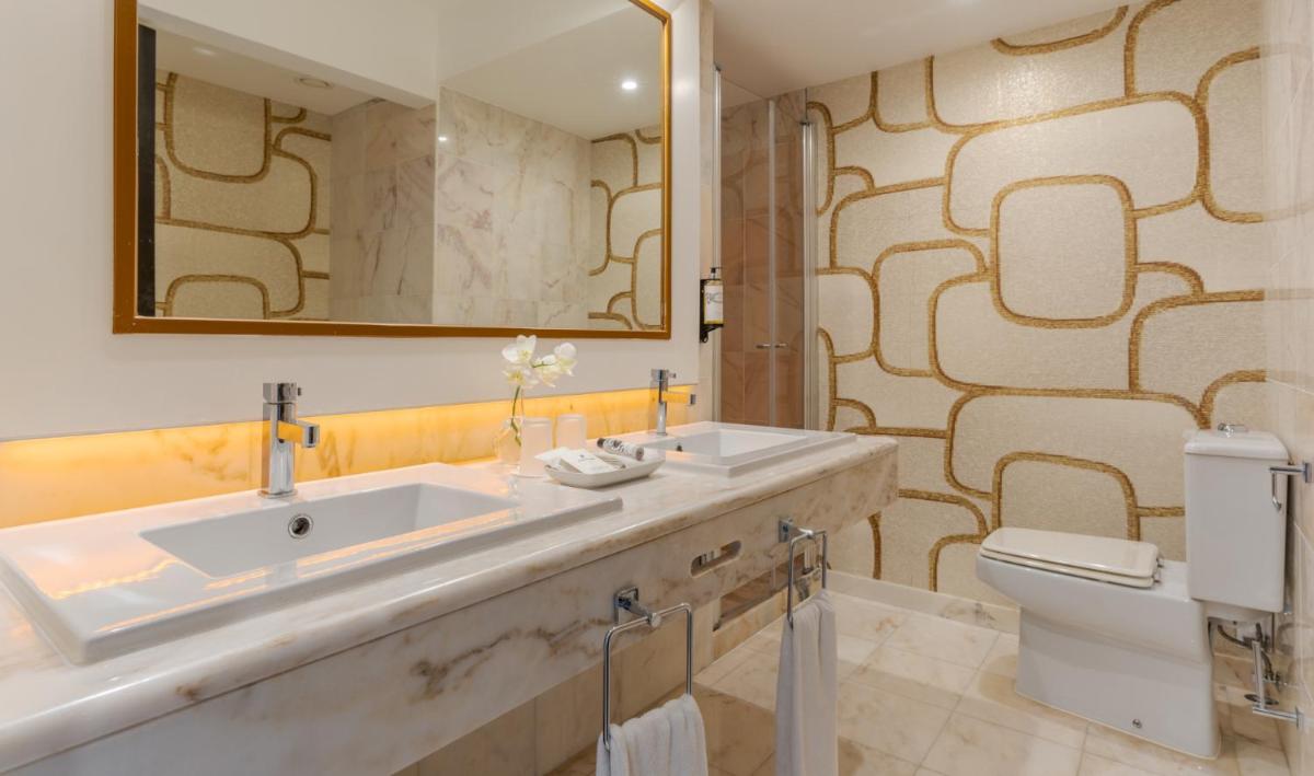 um banheiro com uma pia, um vaso sanitário e um espelho em Pestana Alvor Praia Premium Beach & Golf Resort em Alvor um banheiro com uma pia, um vaso sanitário e um espelho em Pestana Alvor Praia Premium Beach & Golf Resort em Alvor