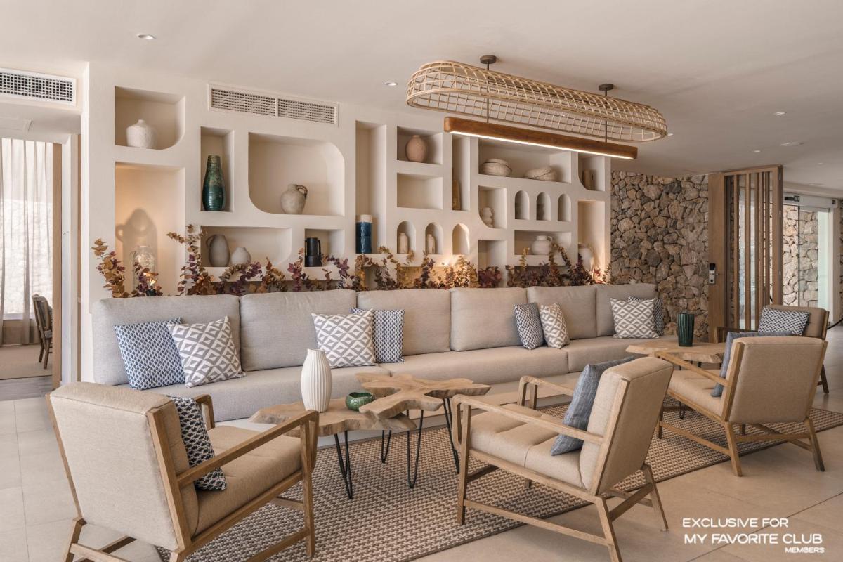 Una sala de estar con un sofá, mesas y sillas. en AluaSoul Mallorca Resort - Adults only, en Cala d´Or