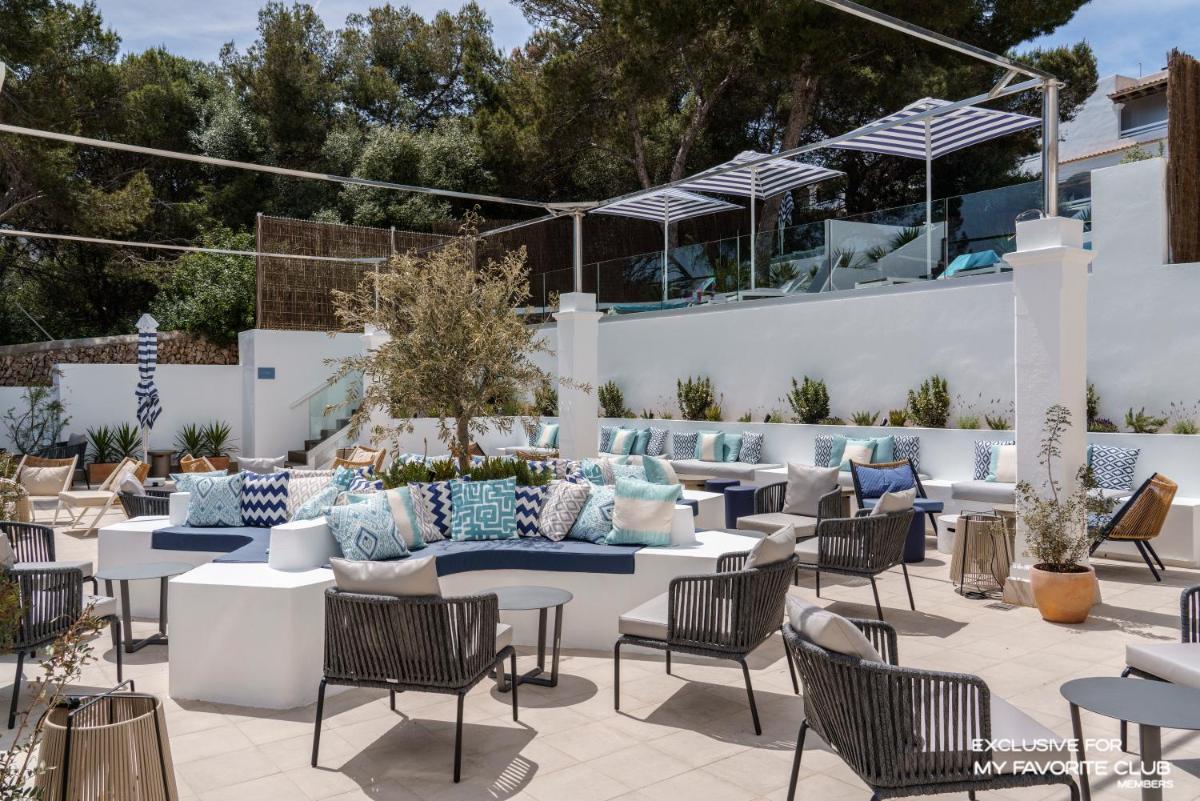Un patio con sofás, mesas y sillas. en AluaSoul Mallorca Resort - Adults only, en Cala d´Or