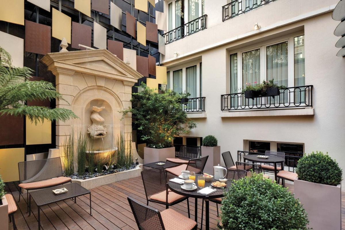une terrasse extérieure avec tables et chaises et une fontaine dans l'établissement Rochester Champs Elysees, à Paris