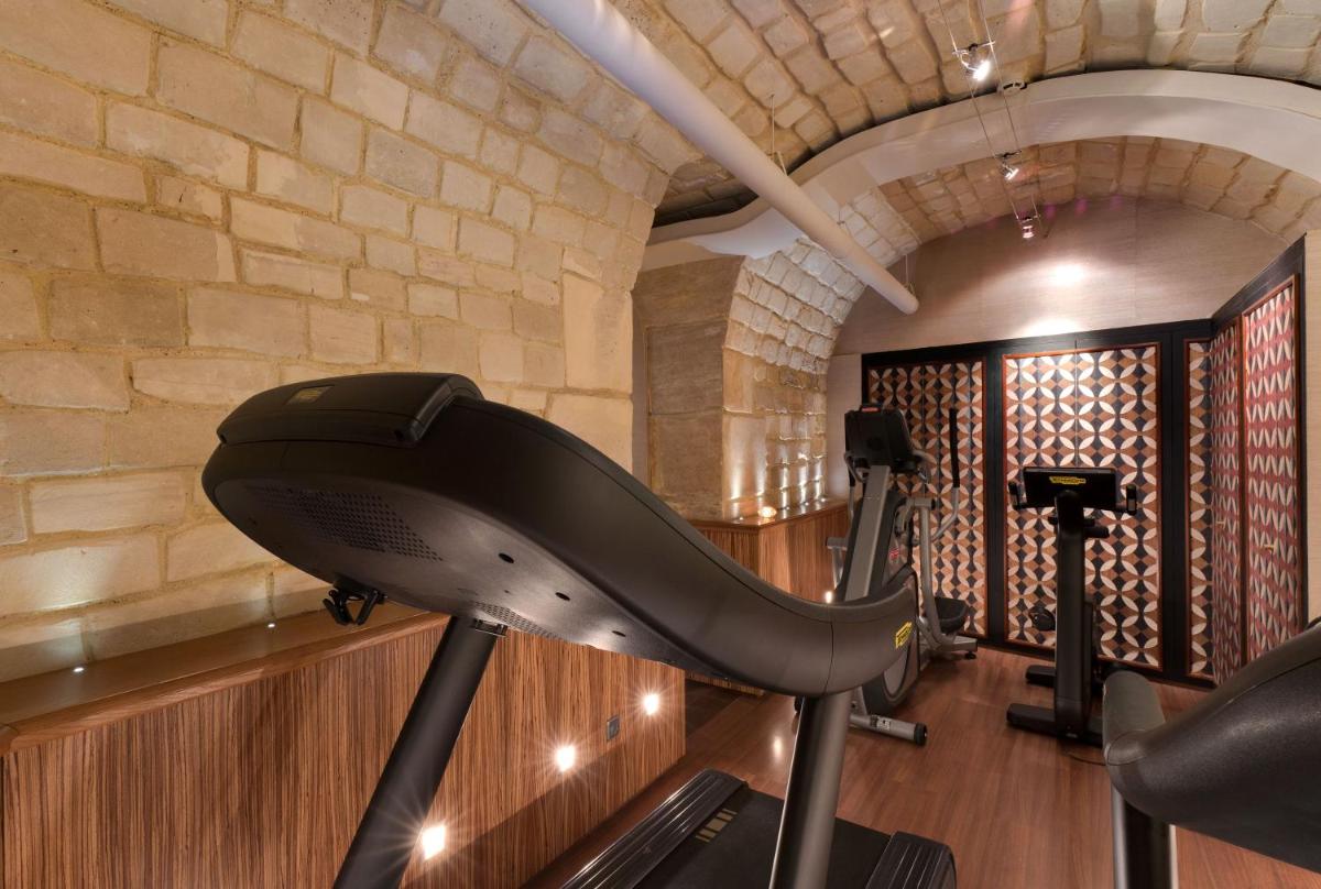une salle de sport avec un tapis roulant et un mur de briques dans l'établissement Rochester Champs Elysees, à Paris