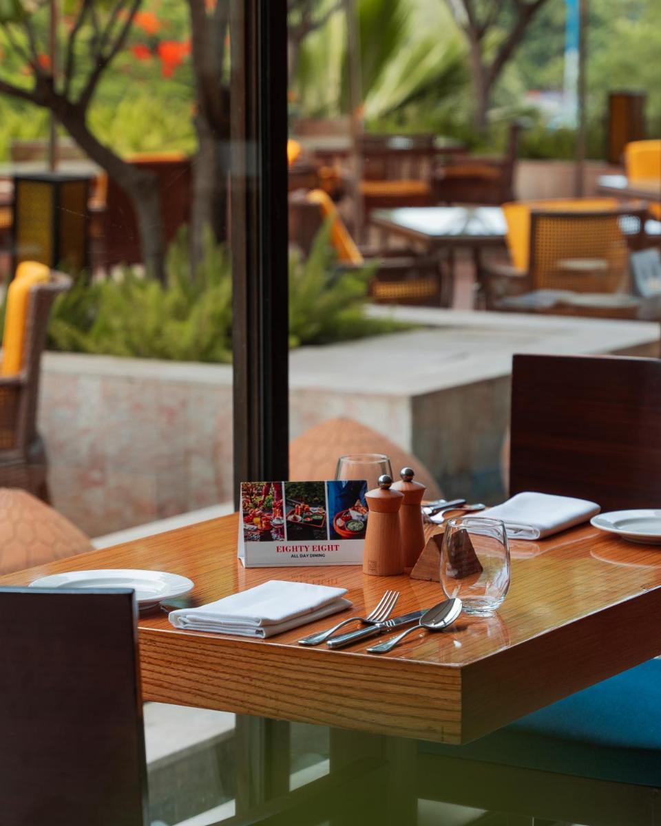 a wooden table with utensils and a book on it at Hyatt Pune in Pune