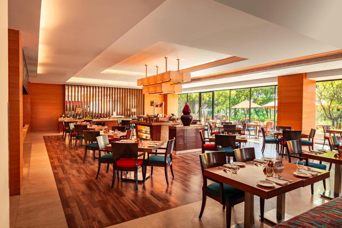 a dining room with tables and chairs and a restaurant at Hyatt Pune in Pune