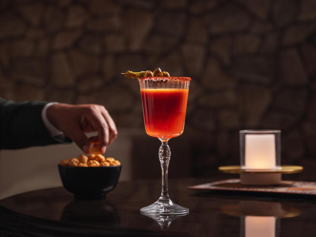 a person placing a drink in a martini glass on a table at Hyatt Pune in Pune