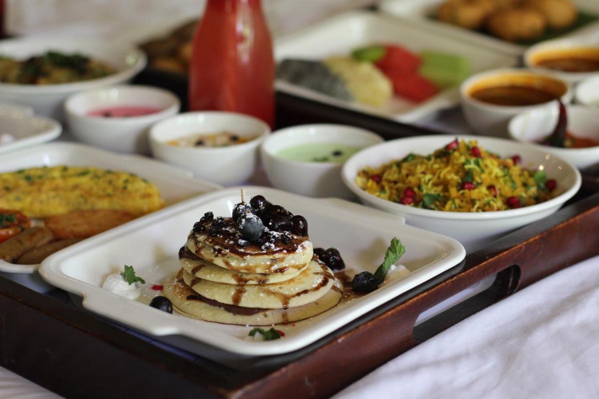 a tray filled with plates of food on a table at Le Meridien Jaipur Resort & Spa in Jaipur