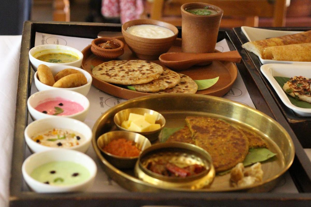 a tray filled with various types of food on a table at Le Meridien Jaipur Resort & Spa in Jaipur