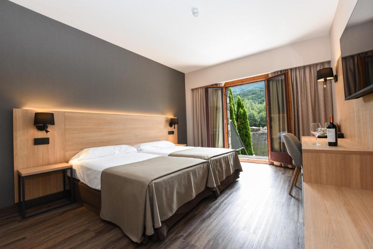 Una habitación de hotel con una cama y una ventana. en SOMMOS Hotel Benasque Spa, en Benasque
