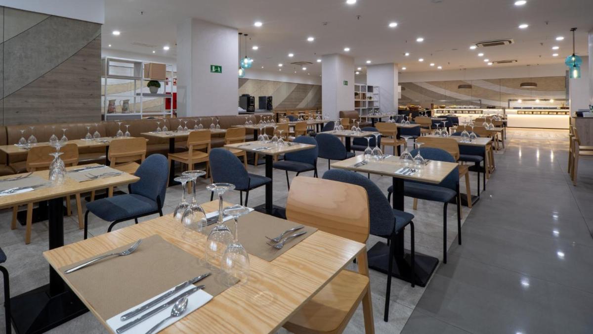 Un restaurante con mesas de madera y sillas azules. en Hotel AF Valle Orotava, en Puerto de la Cruz