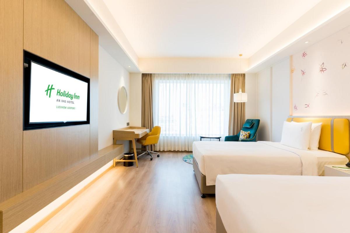 a hotel room with two beds and a flat screen tv at Holiday Inn Lucknow Airport by IHG in Lucknow