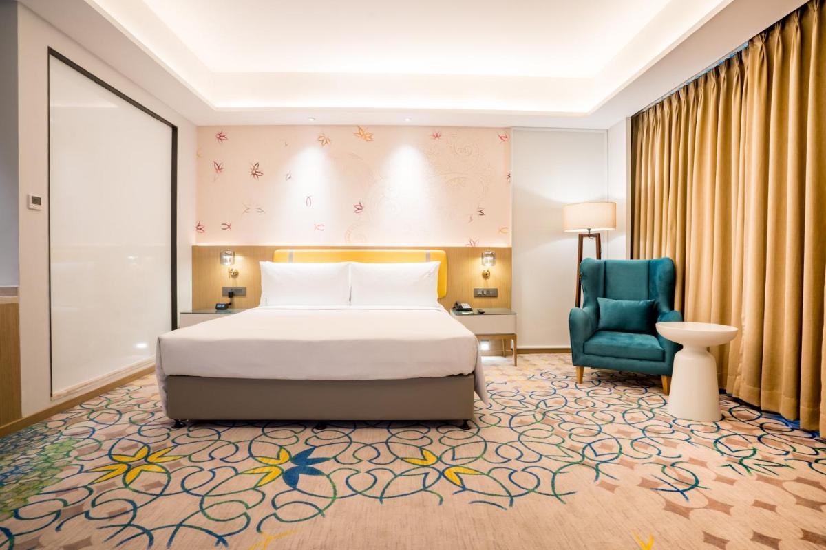 a bedroom with a bed and a blue chair at Holiday Inn Lucknow Airport by IHG in Lucknow