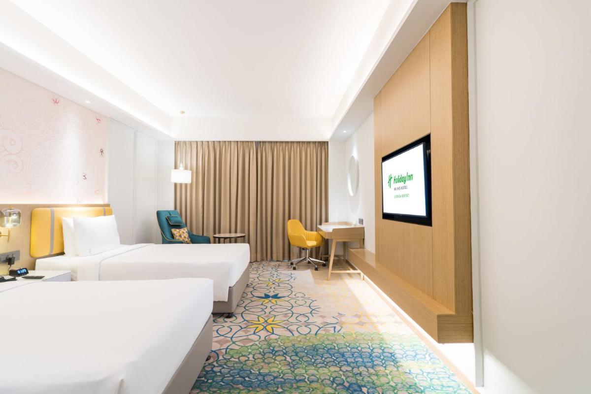 a hotel room with two beds and a flat screen tv at Holiday Inn Lucknow Airport by IHG in Lucknow