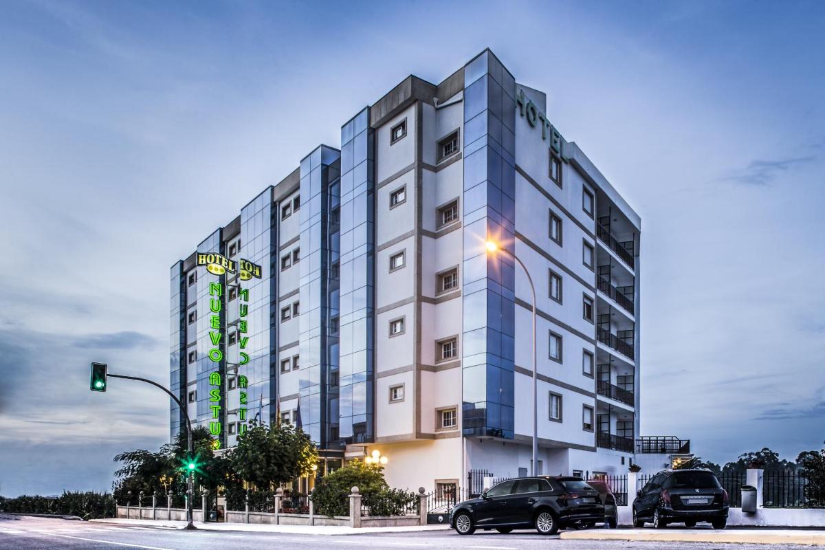 Un edificio alto con coches aparcados delante. en Nuevo Astur Spa, en Sanxenxo