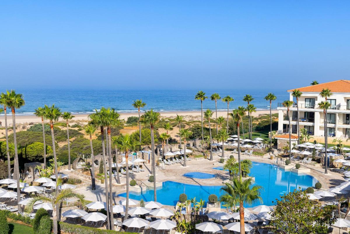 Una vista aérea de un resort con piscina y playa. en Hipotels Barrosa Palace & Spa, en Chiclana de la Frontera