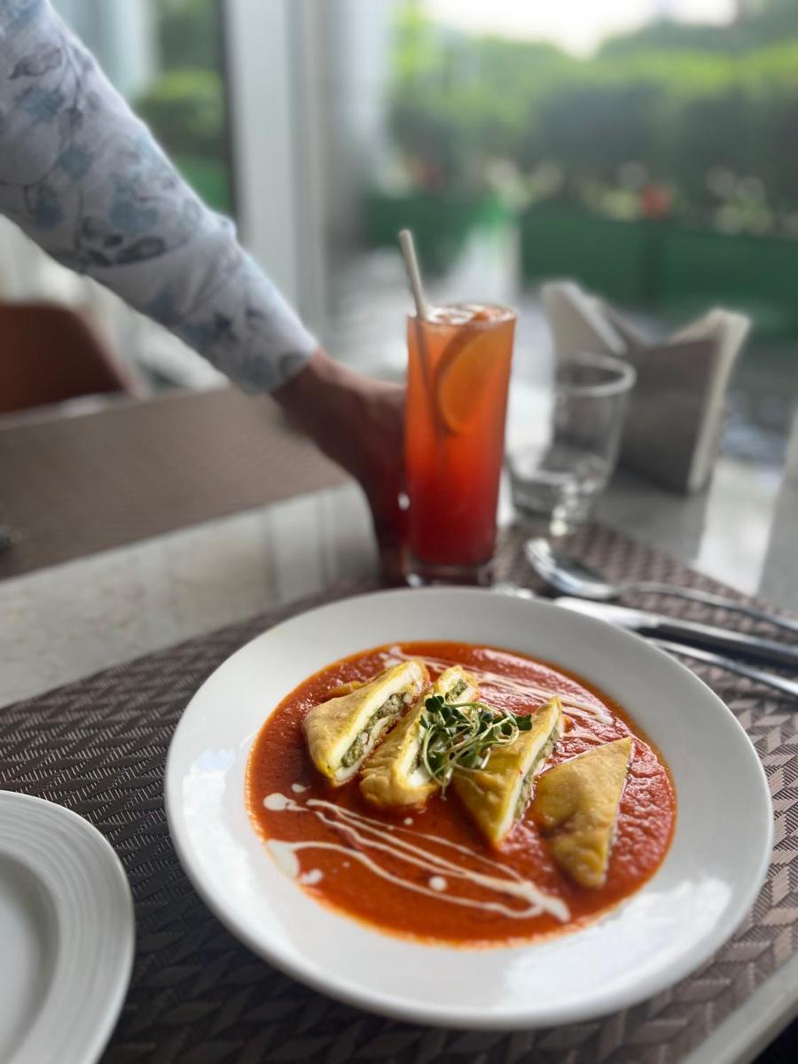 a plate of food on a table with a drink at Holiday Inn New Delhi Aerocity by IHG in New Delhi