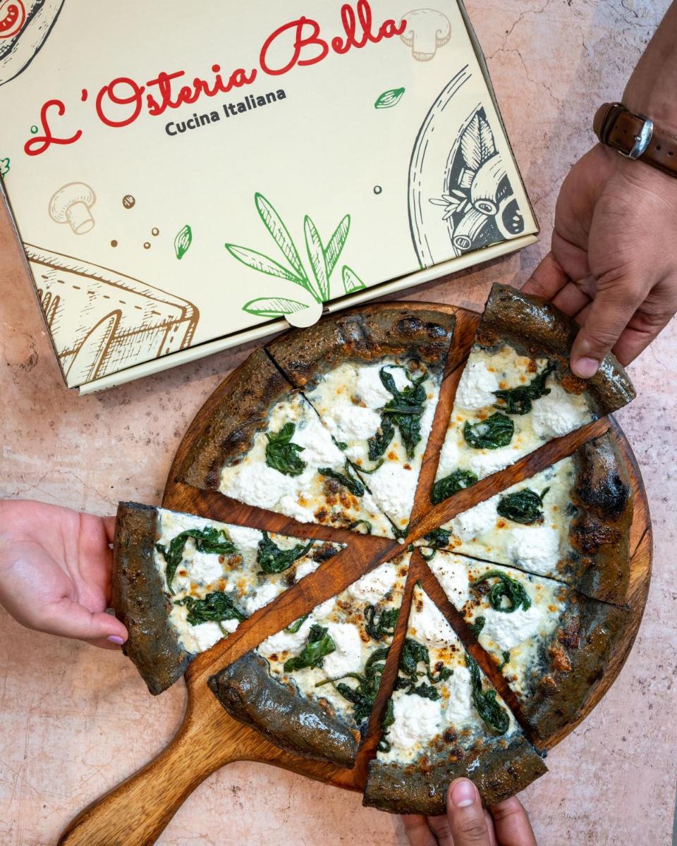 a person holding a pizza in front of a pizza box at Holiday Inn New Delhi Aerocity by IHG in New Delhi