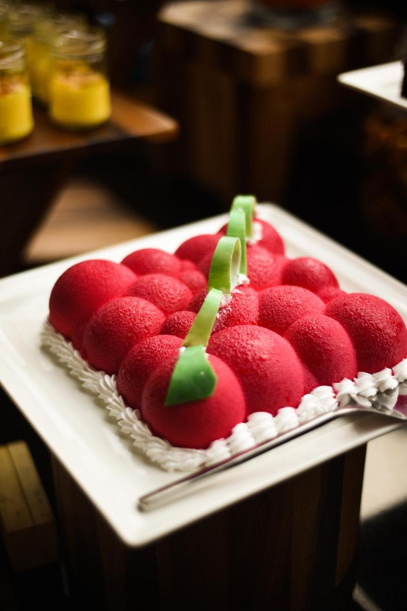 a cake with red strawberries on a white plate at Holiday Inn New Delhi Aerocity by IHG in New Delhi