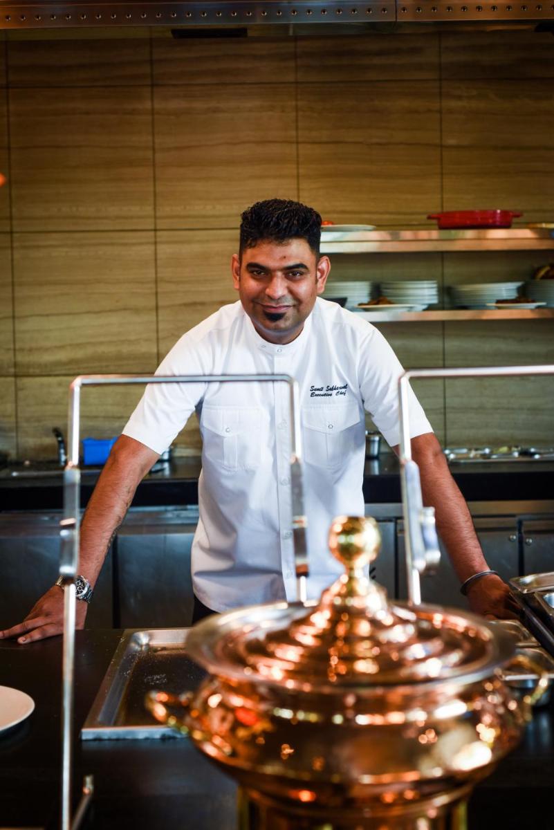 a man standing in a kitchen preparing food at Holiday Inn New Delhi Aerocity by IHG in New Delhi