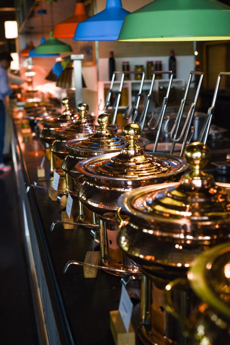 a row of copper kettles lined up on a counter at Holiday Inn New Delhi Aerocity by IHG in New Delhi