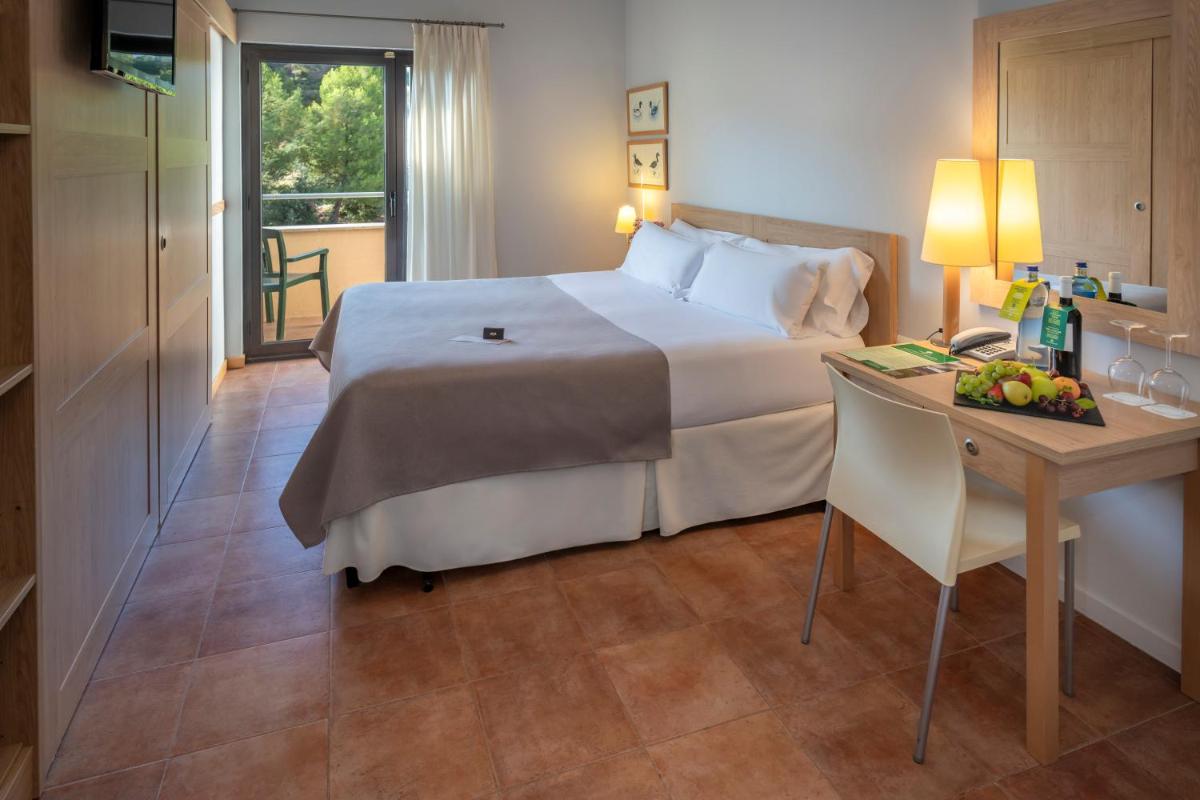 Una habitación de hotel con una cama y un escritorio con una computadora. en Hotel & Resort Vilar Rural d'Arnes by Serhs Hotels, en Arnes