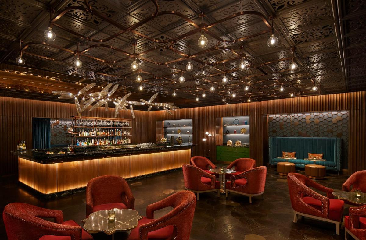 a restaurant with red chairs and a bar at Taj Amer, Jaipur in Jaipur