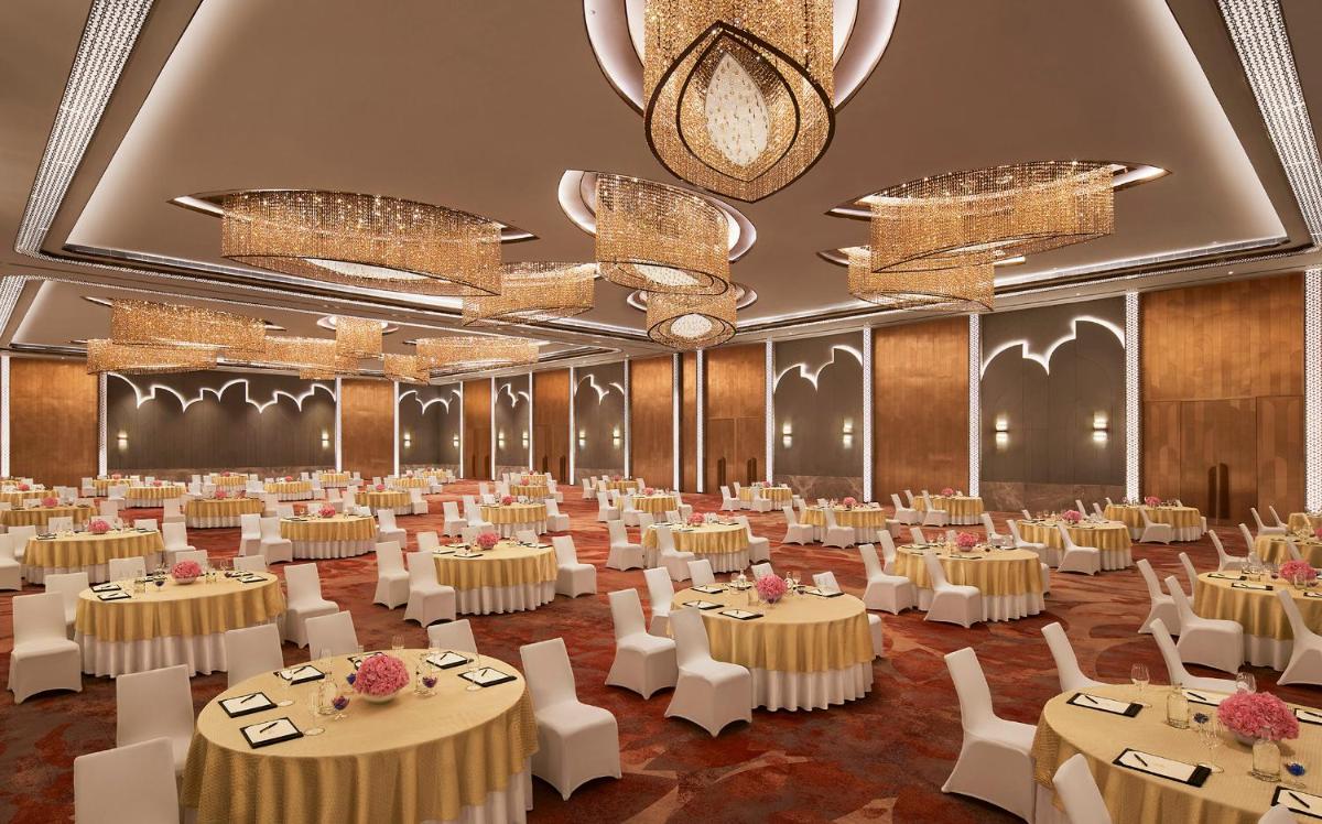 a banquet hall with white tables and chairs and chandeliers at Taj Amer, Jaipur in Jaipur