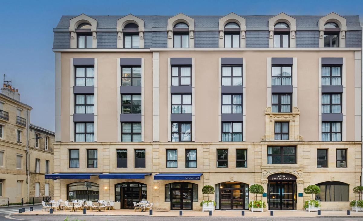un grand bâtiment bien exposé avec un toit gris dans l'établissement Hôtel Burdigala by Inwood Hotels, à Bordeaux
