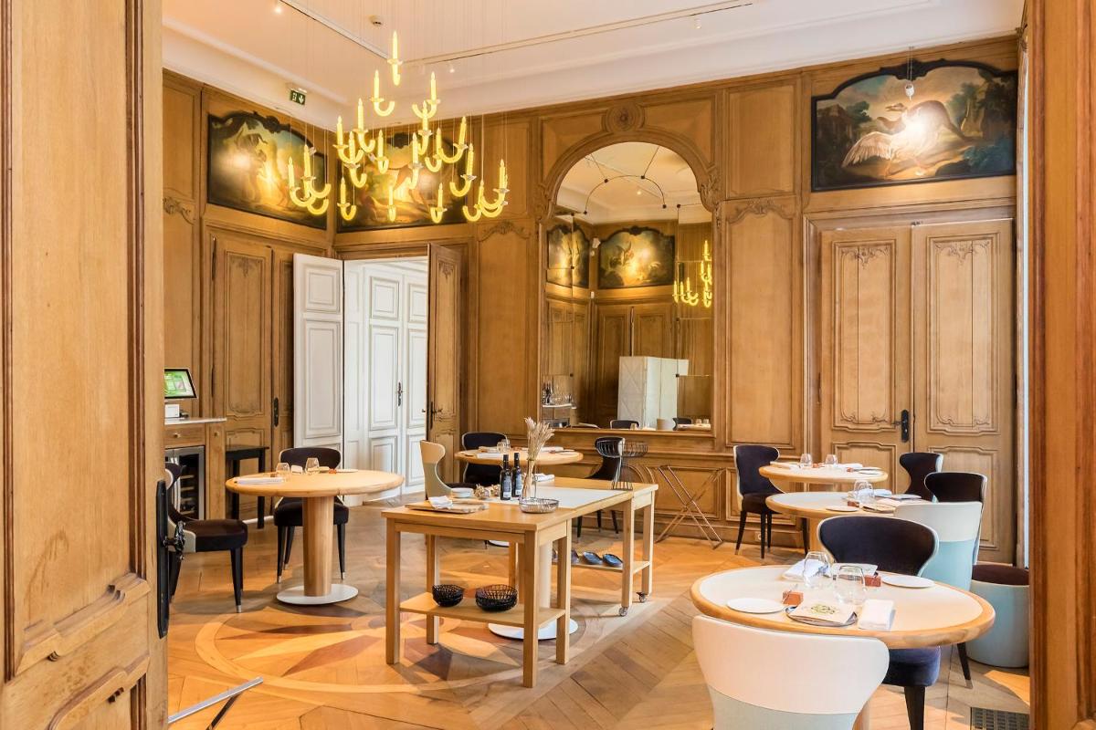 un restaurant avec des tables, des chaises et un lustre dans l'établissement Clarance Hotel Lille, à Lille un restaurant avec des tables, des chaises et un lustre dans l'établissement Clarance Hotel Lille, à Lille