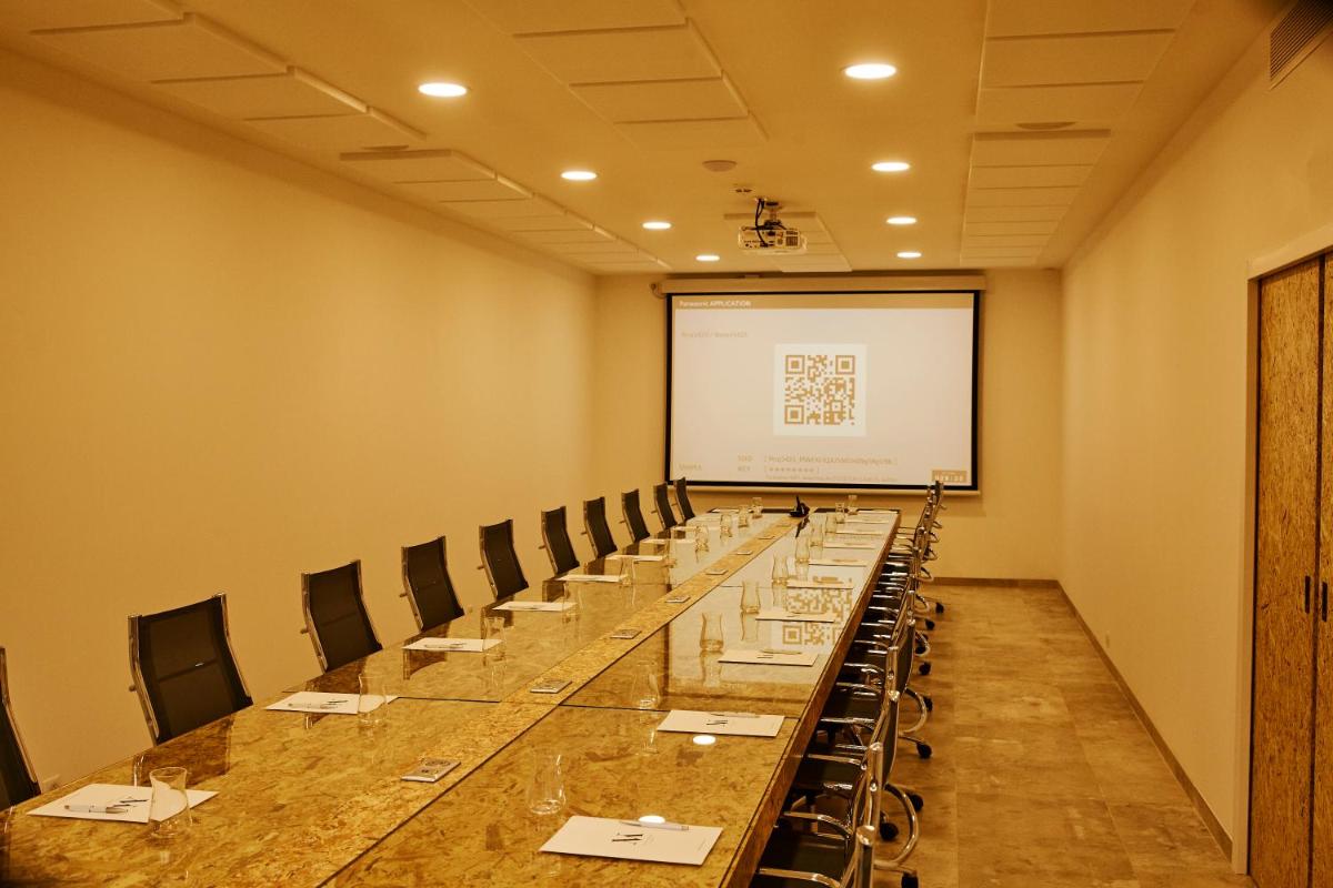 une salle de conférence avec une grande table et un écran blanc dans l'établissement Hôtel & Spa Version Maquis Citadelle, à Bonifacio 37 autres photos