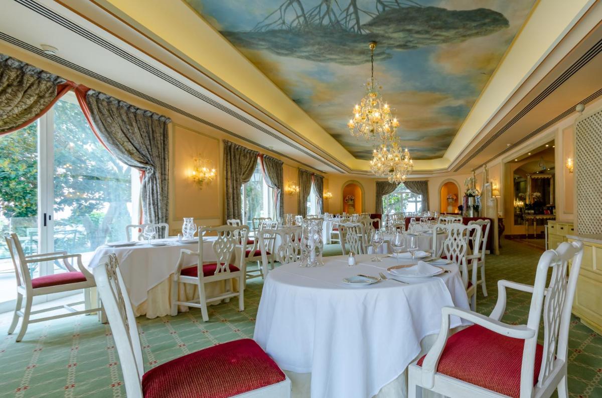 uma sala de jantar com mesas e cadeiras brancas em Olissippo Lapa Palace – The Leading Hotels of the World em Lisboa