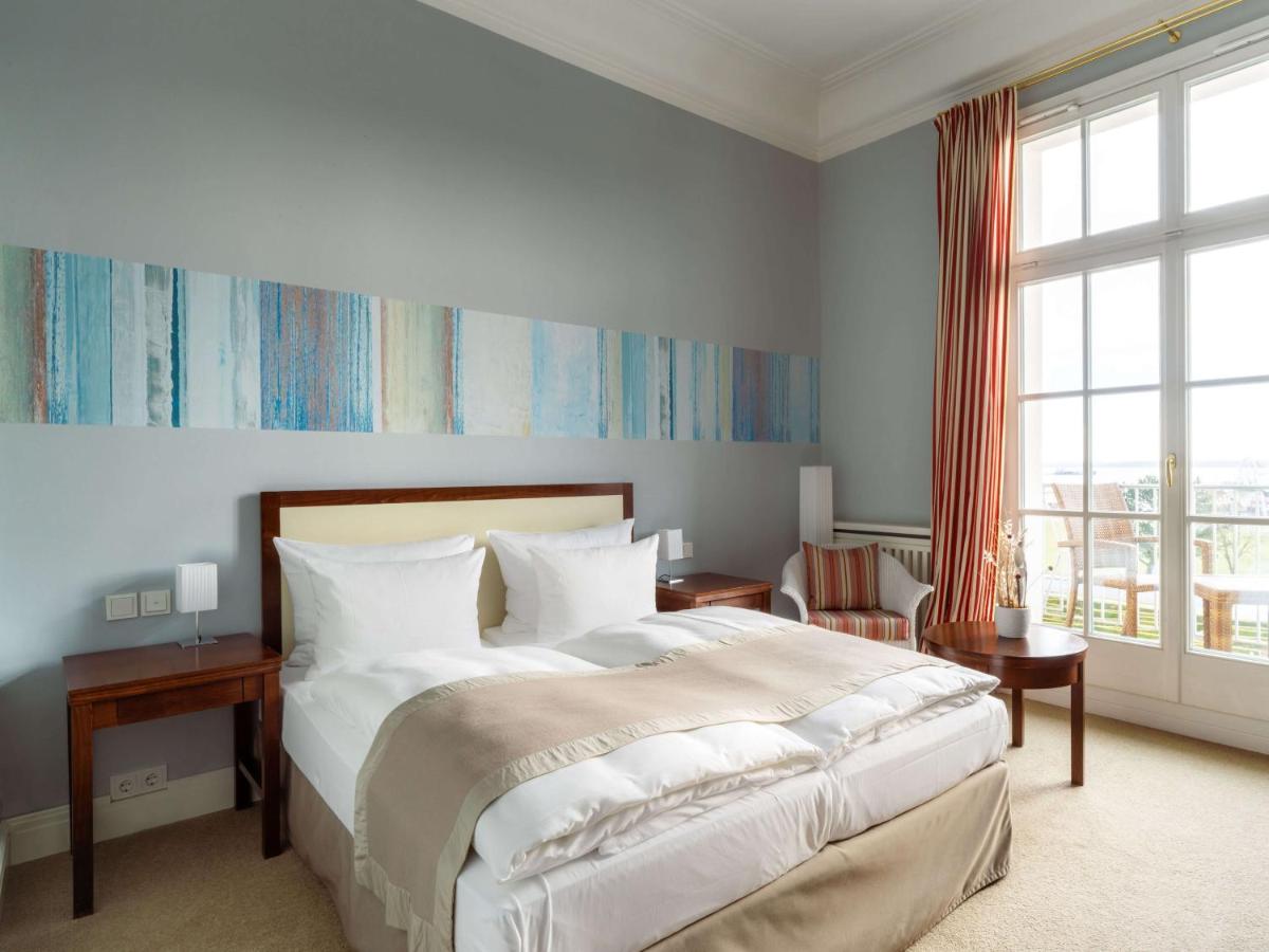 ein Schlafzimmer mit einem großen Bett und einem großen Fenster in der Unterkunft A-ROSA Travemünde in Travemünde