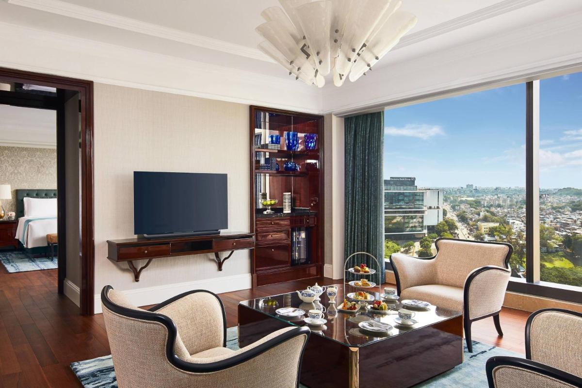 a living room with a television and a large window at The Ritz-Carlton, Pune in Pune