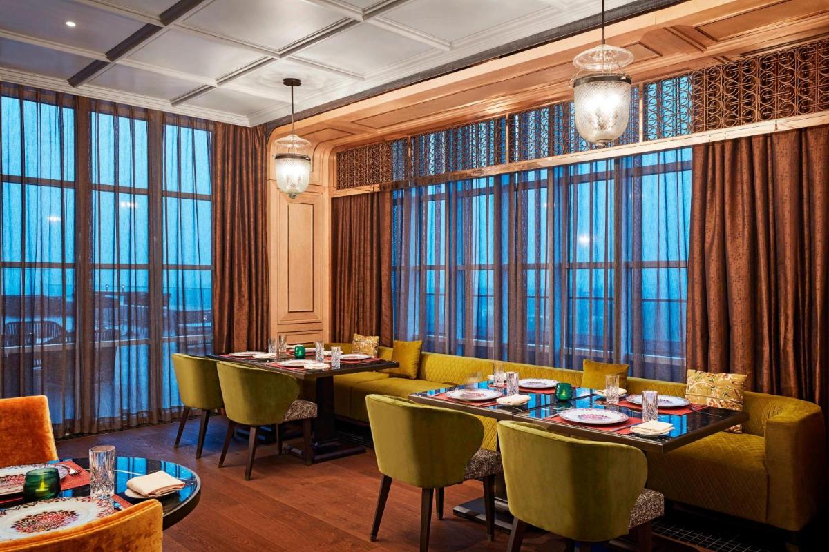 a restaurant with tables and chairs and large windows at The Ritz-Carlton, Pune in Pune
