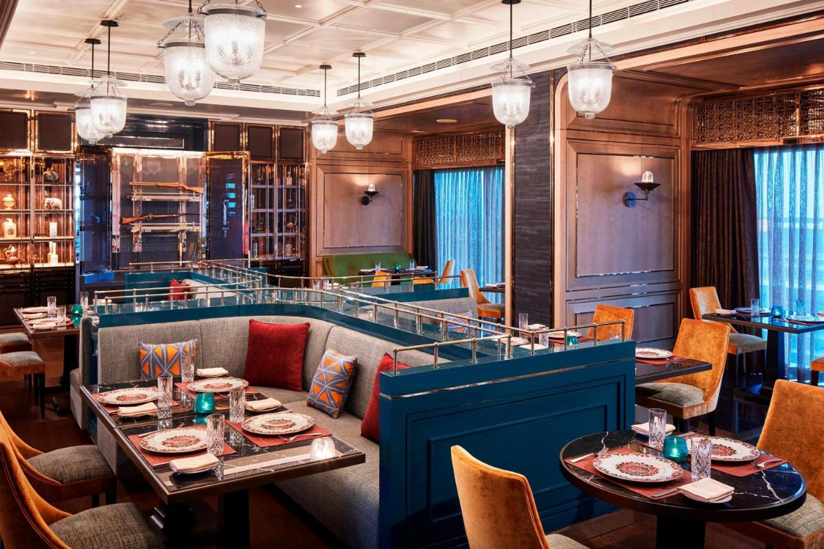 a dining room with tables and chairs and chandeliers at The Ritz-Carlton, Pune in Pune