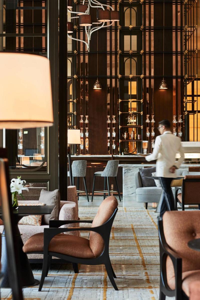 a man walking through a lobby with chairs and tables at The Ritz-Carlton, Pune in Pune