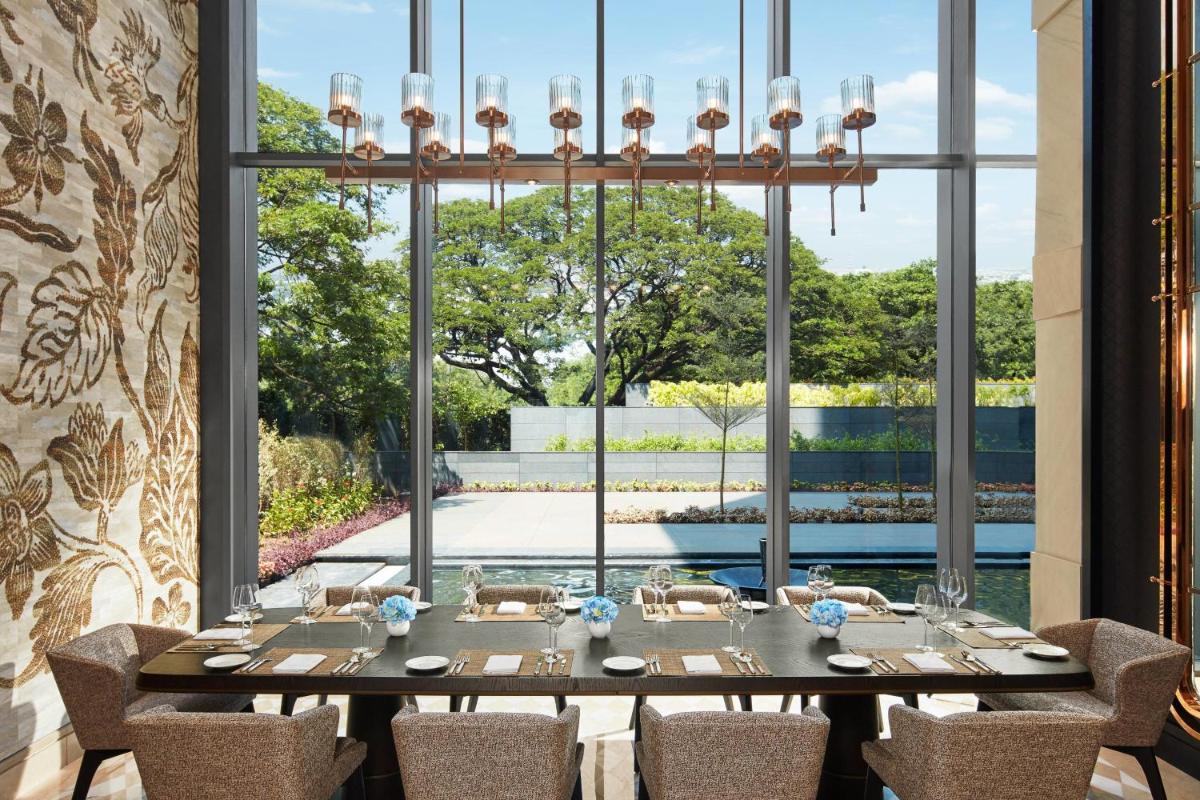a dining room with a table with chairs and a large window at The Ritz-Carlton, Pune in Pune