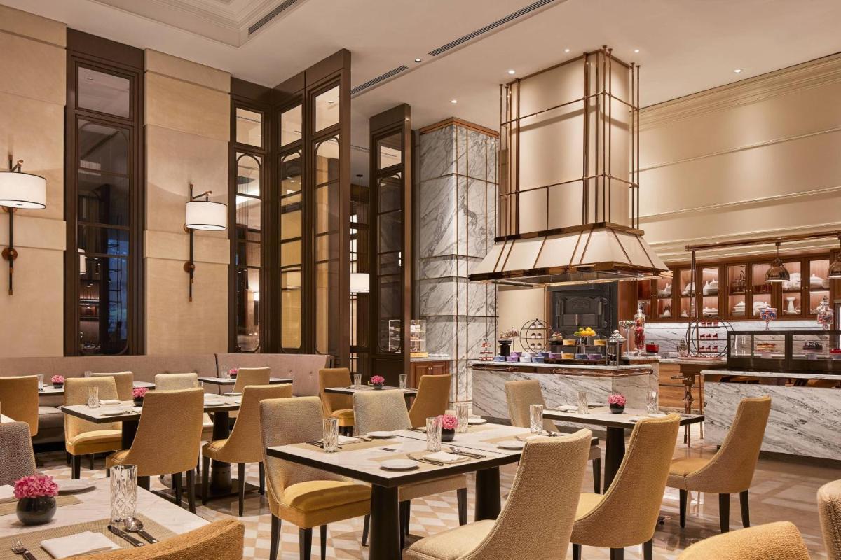 a restaurant with tables and chairs and a kitchen at The Ritz-Carlton, Pune in Pune