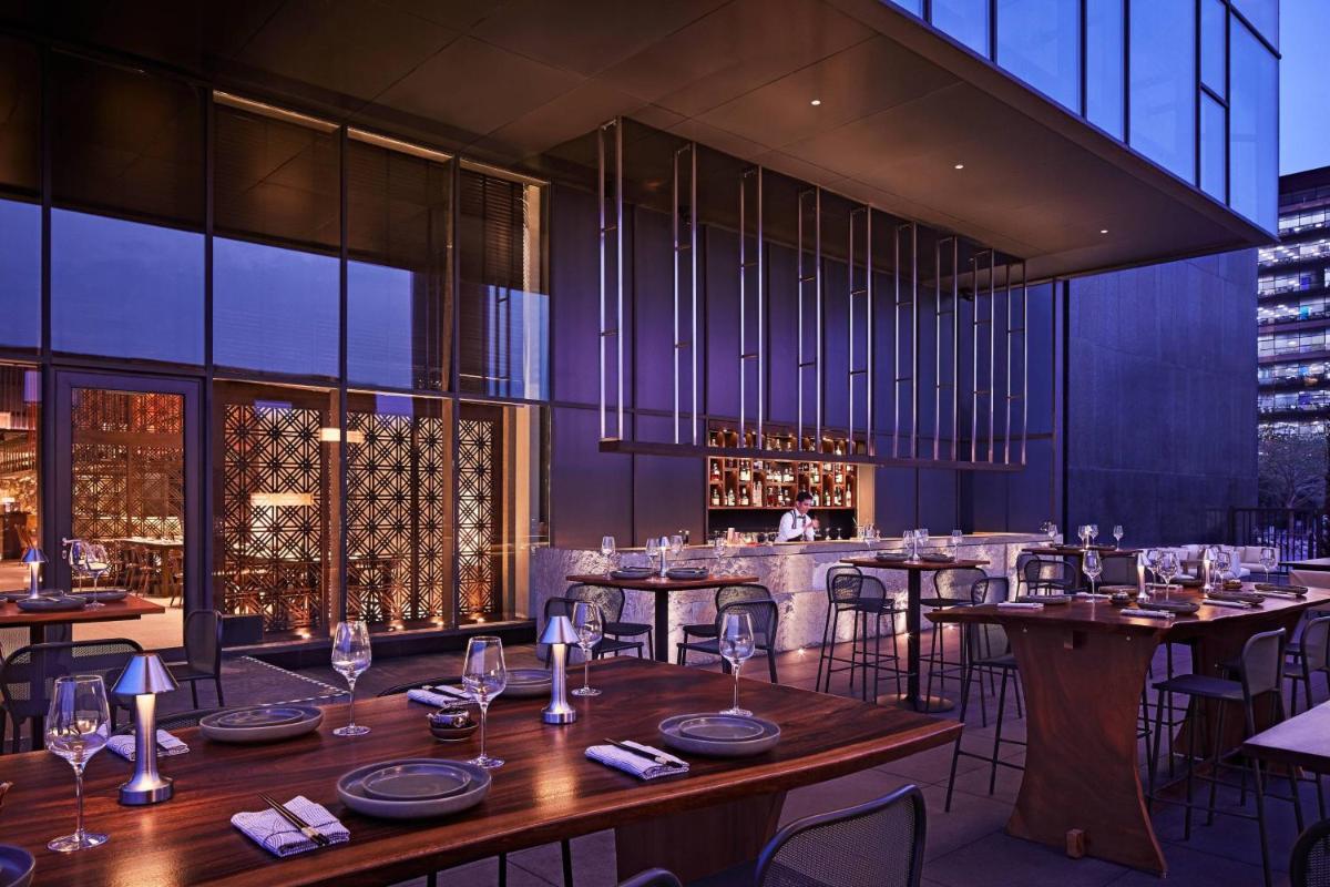 a restaurant with wooden tables and chairs and wine glasses at The Ritz-Carlton, Pune in Pune