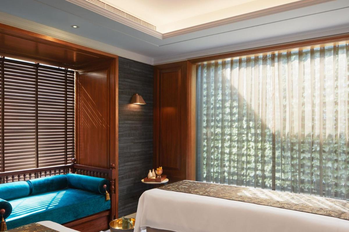 a bedroom with a bed and a window with a blue couch at The Ritz-Carlton, Pune in Pune