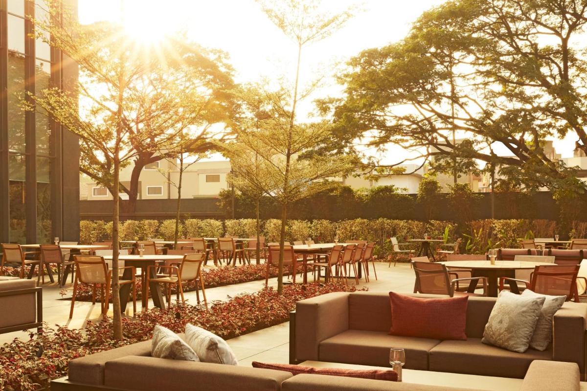 a patio with tables and chairs and the sun shining at The Ritz-Carlton, Pune in Pune
